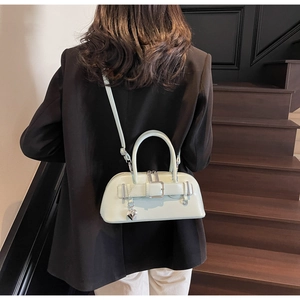 Détail du sac bowling vert menthe avec pendentif coeur porté sur un blazer noir