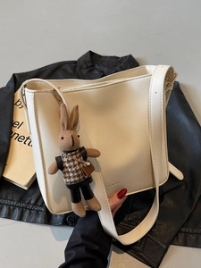 Sac seau blanc minimaliste avec pendentif lapin marron sur une veste en cuir noir