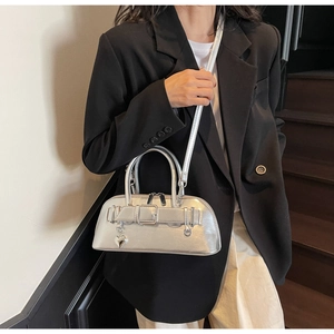 Sac bowling argenté métallisé avec pendentif cœur porté par un mannequin en costume
