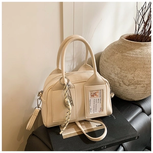Detail of cream Boston bag with ID card slot and decorative knot on leather pedestal