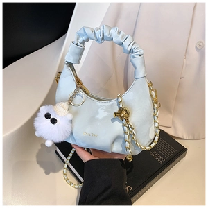 Détail du sac croissant plissé bleu clair avec chaîne dorée et porte-clés peluche