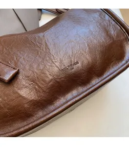 Detailed view of the soft textured dark brown leather surface with embossed brand logo