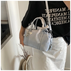 Detail of light blue Boston bag with lace bow and heart charm on a crossbody strap