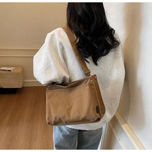 Brown canvas crossbody tote bag worn by model in a minimalist cozy indoor setting