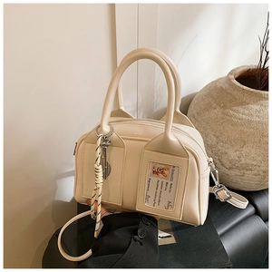 Detail of cream Boston bag featuring unique front card slot and textured matte leather finish