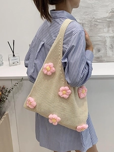 Beige crochet tote bag with pink 3D flowers shown on a model wearing a striped dress