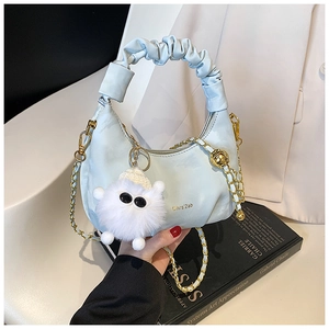 Détail d'un sac à main bleu clair plissé avec chaîne dorée et breloque peluche