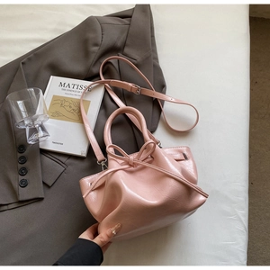 Detailansicht einer rosa plissierten Beuteltasche mit Schleife und glänzendem Finish
