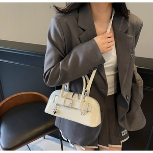 Détail d'un sac bowling blanc brillant avec pendentif coeur et boucles métalliques élégantes