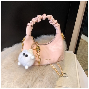 Détail du sac à main plissé rose avec chaîne dorée et breloque en peluche douce