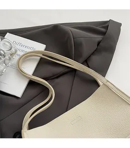Close-up of minimalist cream tote bag showing soft pebbled leather texture and dual straps