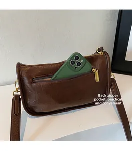 Close-up of the back zipper pocket on a brown vintage crossbody bag for phone storage