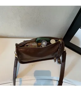 Spacious interior of retro brown cylindrical bag showing phone and perfume storage