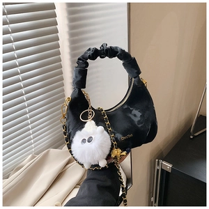Détail du sac croissant plissé noir avec chaîne dorée et pendentif chat peluche