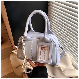Detail of light blue crossbody bag featuring clear card slot and tennis racket charm