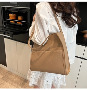 Detail of tan lychee pattern leather tote bag shown on shoulder in a modern kitchen