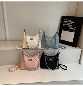 Detailed shot of quilted chain bags in white, blue, pink and black on marble steps