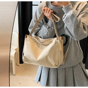 Detail of beige canvas tote bag featuring brown leather trim and adjustable strap