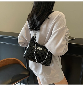 Quilted black leather shoulder bag with silver chain strap shown on a model