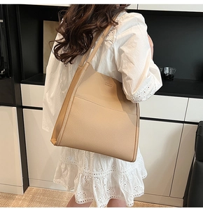 Detail view of large beige tote bag featuring high-quality lychee texture and slim straps