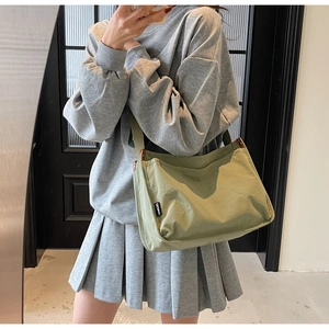 Green canvas tote bag with adjustable wide strap shown in a stylish casual crossbody view