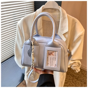 Detail of light blue Boston bag with dual handles, tennis racket charm and ID card slot