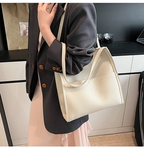 Close-up of off-white lychee pattern leather tote bag with side accordion folds