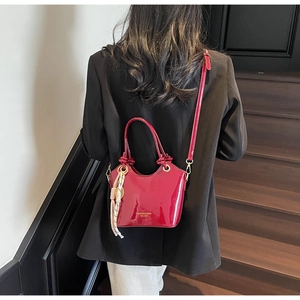 Detalle de bolso bucket rojo en cuero encerado con pañuelo de seda y logo oro