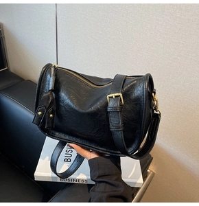 Detail view of black vintage leather bag with golden zipper and textured surface
