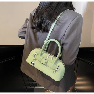 Sac bowling vert menthe avec pendentif cœur porté par un mannequin en blazer gris