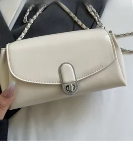 Close-up of cream chain crossbody bag with silver oval lock and textured faux leather