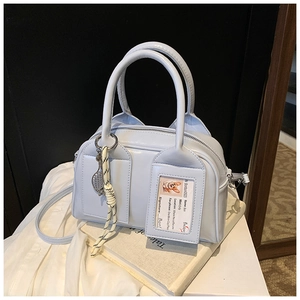 Close-up of light blue Boston bag with woven knot detail and decorative ID card slot