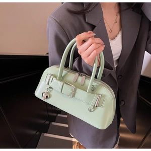 Détail du sac à main en cuir vert clair avec breloque cœur argentée et boucle de ceinture