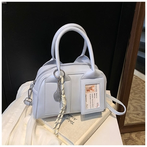 Detail of light blue Boston bag featuring tennis racket charm and transparent card slot