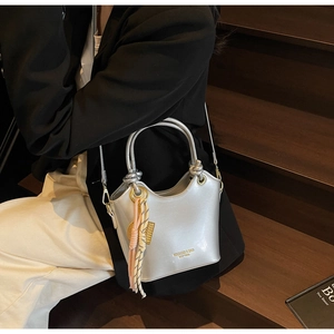 Bolso cubo plateado con colgante de cuerda trenzada en escaleras de madera
