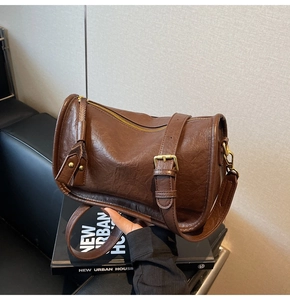 Detail showing deep brown vintage cylinder bag with textured leather and gold hardware