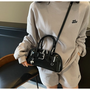 Gros plan du sac bowling en cuir verni noir avec breloque cœur et boucle de ceinture