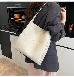 Detailed view of beige tote bag featuring lychee grain leather and precise stitching