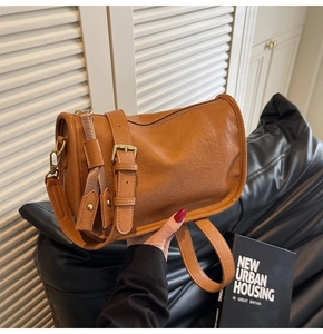 Detail of caramel brown faux leather handbag showing vintage texture and wide shoulder strap
