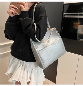 Detail of silver textured leather tote bag with flat front pocket and long shoulder strap