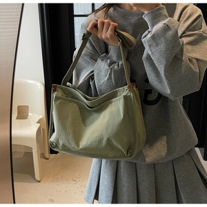 Detail of army green canvas tote bag showing wide adjustable strap and side brand label
