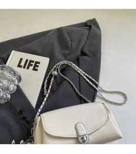 Close-up of beige leather shoulder bag with silver metal twist lock and chain strap detail