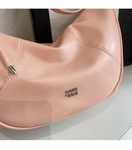 Gros plan d'un sac hobo en cuir rose avec logo COIH 2DN argenté et détails de couture