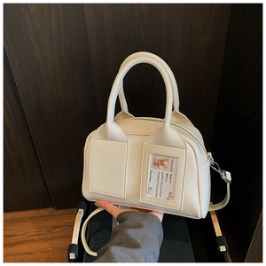 Detailed close-up of a white Boston handbag featuring decorative pockets and card slot
