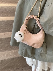 Sac lune plissé rose avec chaîne dorée et breloque pelucheuse sur un mannequin