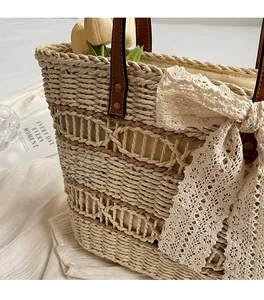 Detail of woven straw tote bag featuring a large lace bow and premium leather handles