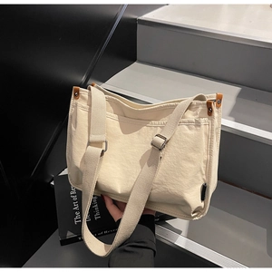 Detail of canvas tote bag with adjustable straps and brown leather accents on stairs