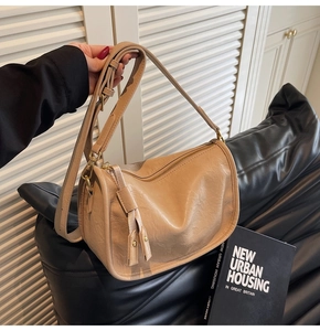 Close-up of beige faux leather cylinder bag with soft pleated texture and adjustable strap