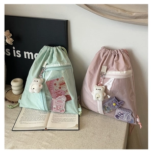 Detail of drawstring canvas backpacks in mint green and pink with clear front pockets