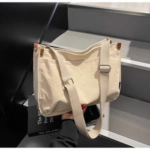 Detail of cream canvas tote bag with brown leather trim and wide adjustable strap